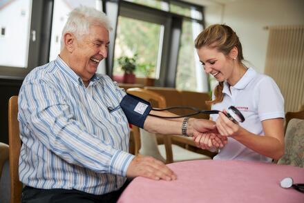 Mitarbeiterin des Ambulanten Pflegedienstes beim Blutdruckmessen 