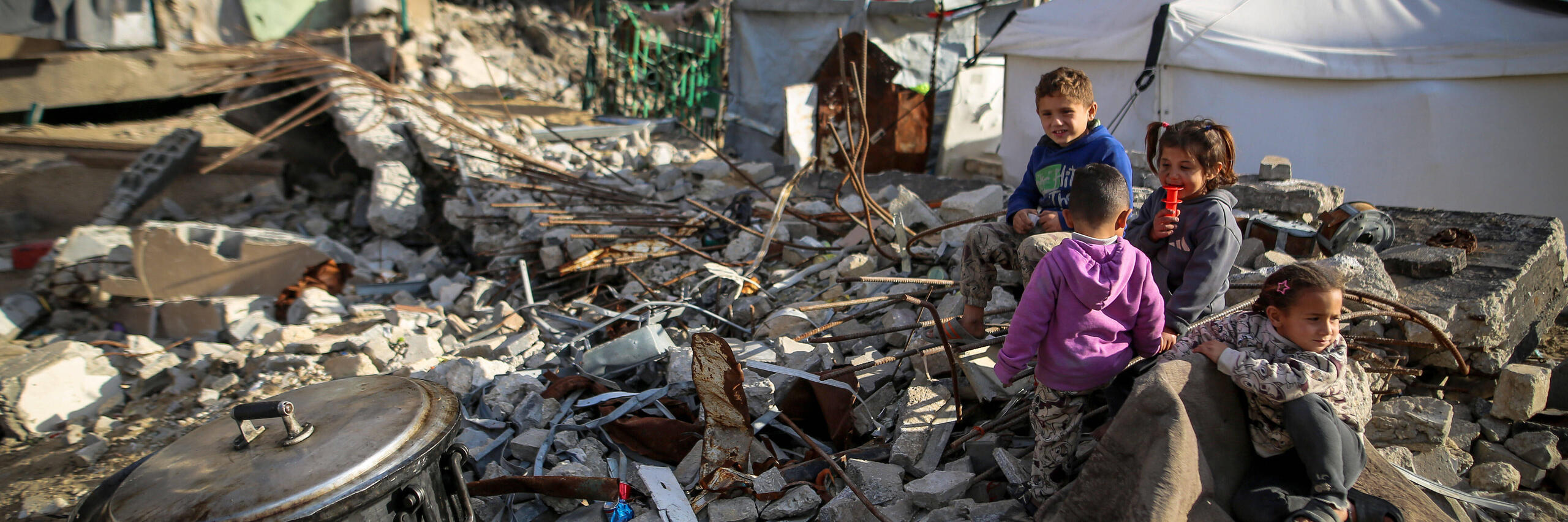 Vier Kinder sitzen in Trümmern im Nahen Osten.