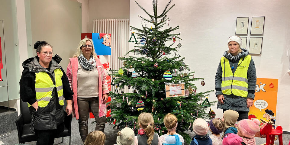 Kinder und drei Frauen bei einem geschmückten Weihnachztsbaum