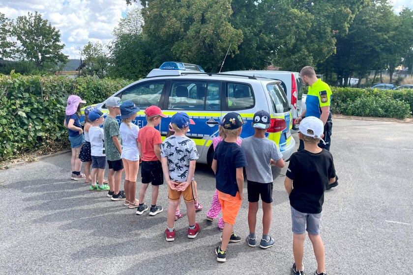 Ein Polizist erklärt Vorschulkindern die Besonderheiten eines Polizeiwagens