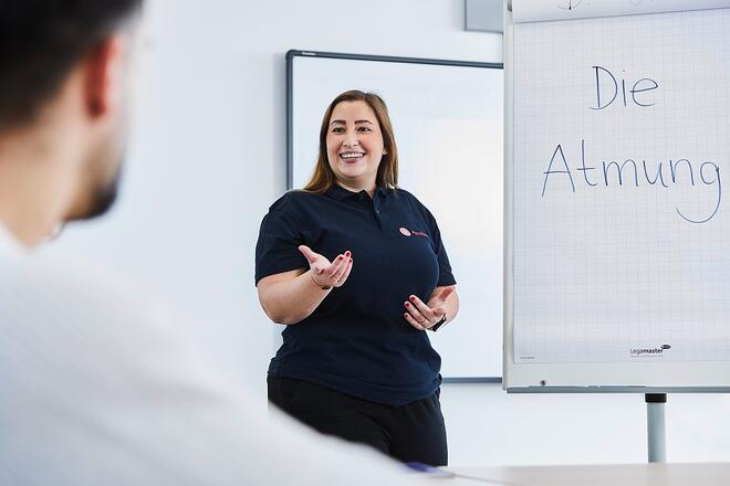 Eine Dozentin steht vor der Klasse und erklärt etwas