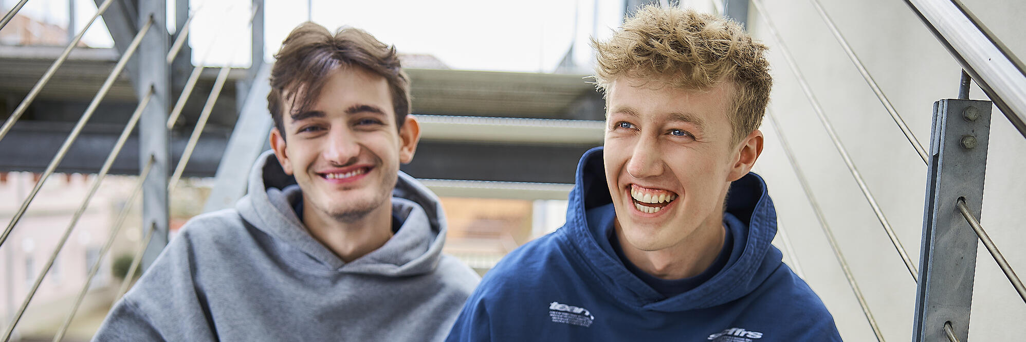 Zwei FSJler sitzen lachend auf einer Treppe.