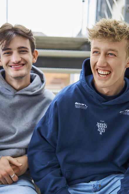 Zwei FSJler sitzen lachend auf einer Treppe.