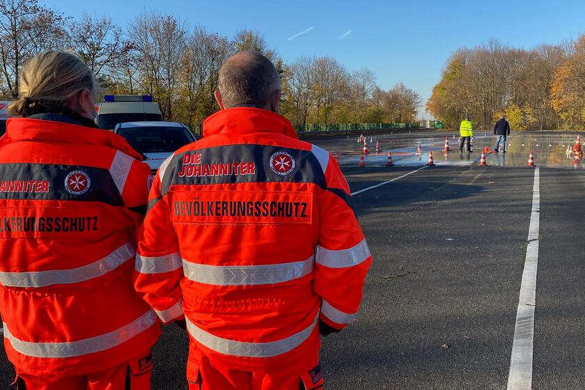 Im Vordergrund: Zwei Ehrenamtliche vom Bevölkerungsschutz / Im Hintergrund: Übungsstraße mit Pilonen für Bremsübung