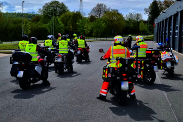 Mehrere Motorräder bzw. Motorradfahrende stehen startbereit vor der Regionalgeschäftsstelle der Johanniter Lippe-Höxter. Einige tragen Einsatzkleidung. Sie starten zu den speziellen Erste-Hilfe-Kurs für Motorradfahrende.
