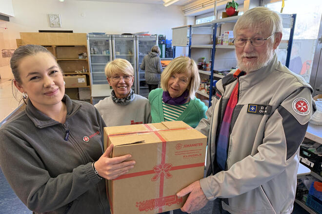 Vier Personen halten ein Paket mit Lebensmitteln.