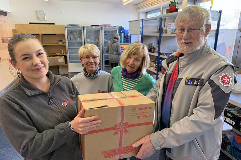 Vier Personen halten ein Paket mit Lebensmitteln.