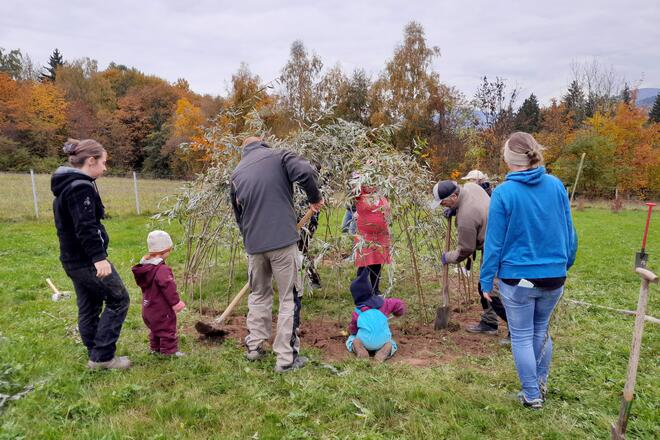 Kinder und Eltern pflanzen den Weidentunnel