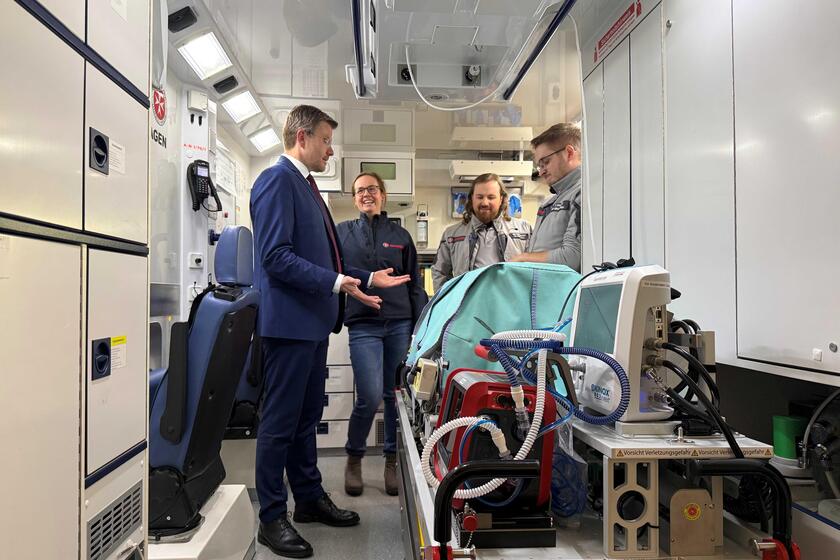 Oberbürgermeister Marcus König steht im Babynotarztwagen mit Johannitern in Einsatzkleidung