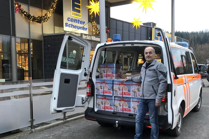 Ein Johanniter vor einem auto, das beladen ist mit Päckchen