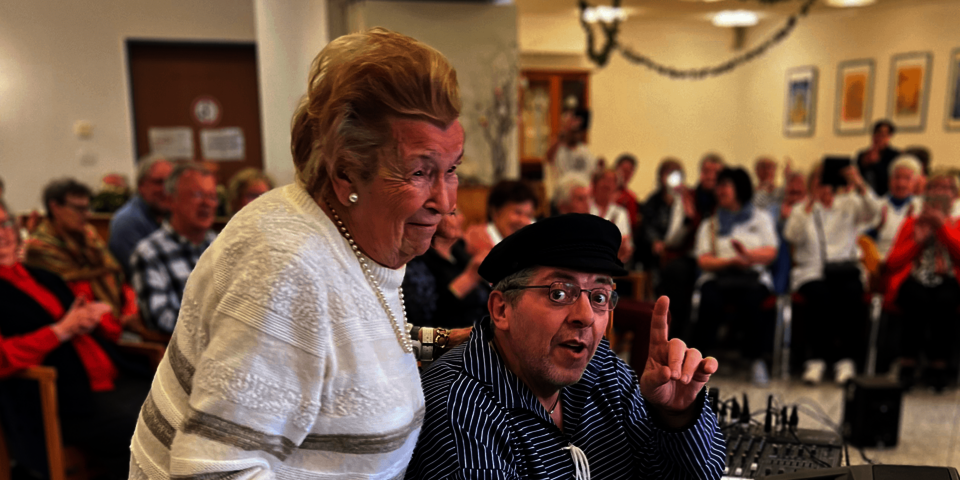 Eine Frau steht hinter einem Mann in blauem Hemd am Keybord