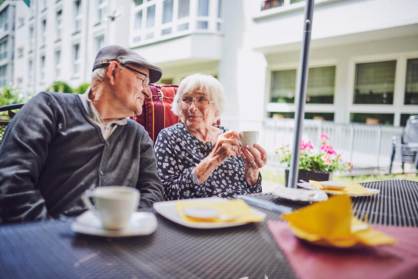 Ein lächelndes Pärchen sitzt an einem schönen gedeckten Kaffeetisch im Johanniter-Stift Gelsenkirchen