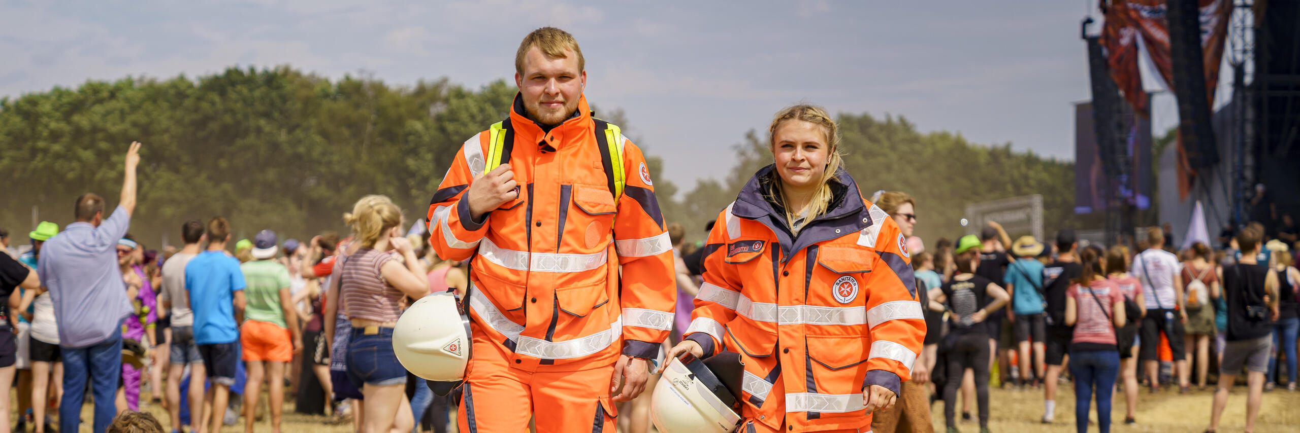 Zwei ehrenamtliche Mitarbeitende im Sanitätsdienst spazieren über ein Festivalgelände.
