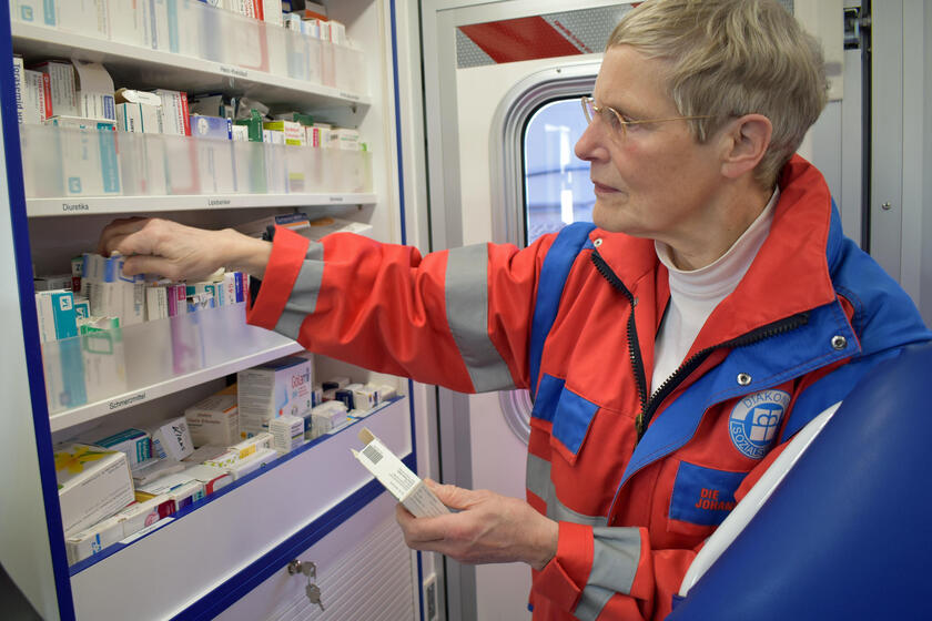 Eine Ehrenamtliche des Gesundheitsmobils räumt Medikamente in einen Schrank.