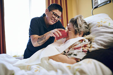 Pflegekraft hilft Bewohnerin beim Trinken