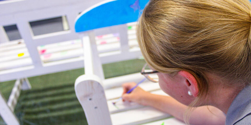 Eine Frau bemalt eine Bank