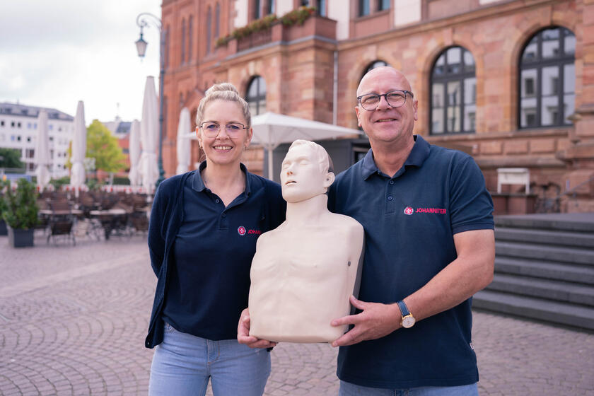 Zwei Erste-Hilfe-Trainees halten eine Reanimationspuppe.