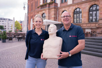 Zwei Erste-Hilfe-Trainees halten eine Reanimationspuppe.
