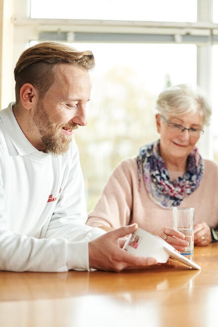 Ein Mitarbeiter der Johanniter-Unfall-Hilfe erklärt einem Neukunden das Hausnotruf-Gerät.