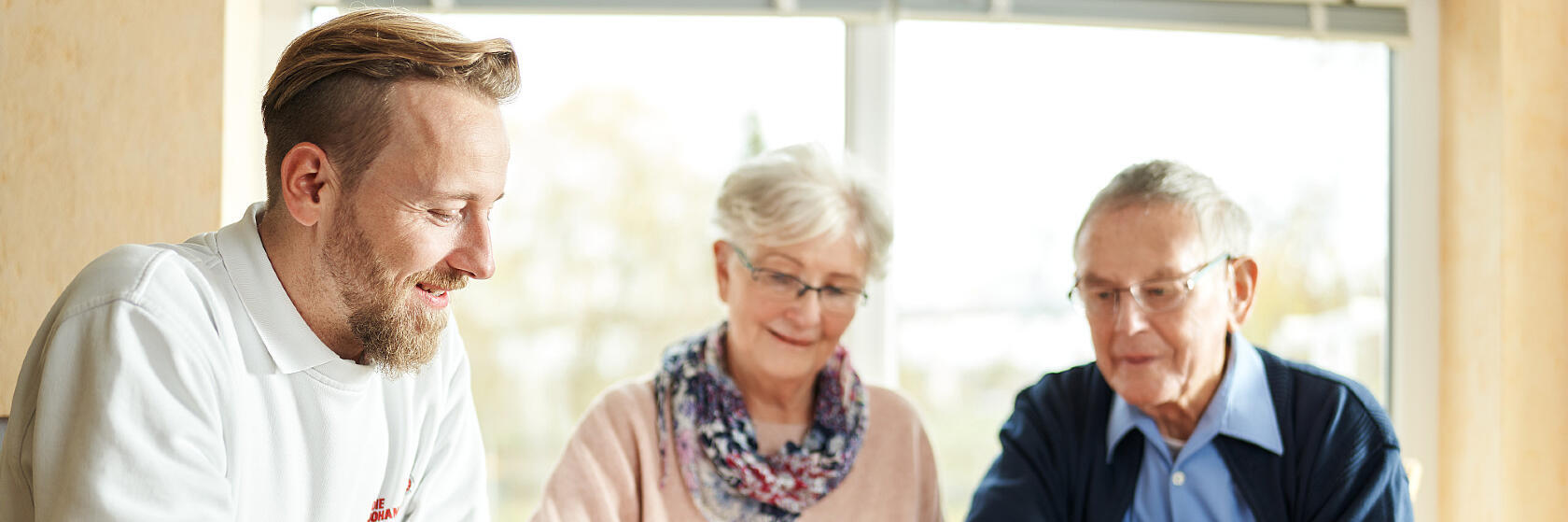 Ein Mitarbeiter der Johanniter-Unfall-Hilfe erklärt einem Neukunden das Hausnotruf-Gerät.