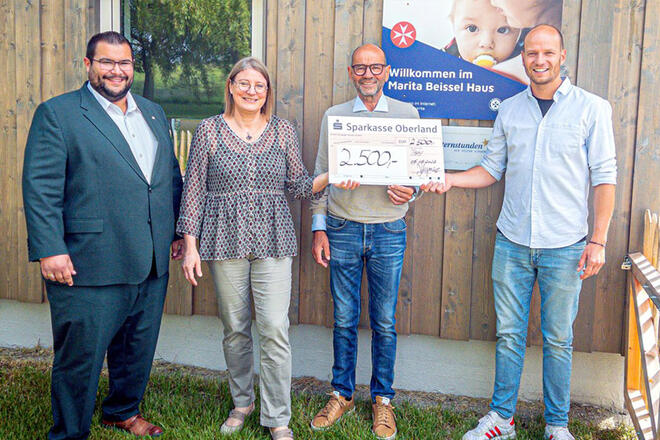 4 Personen stehen vor dem Marita-Beissel-Haus der Johanniter und halten einen großen Spendencheck.