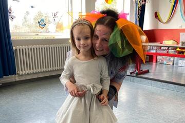 Eine verkleidete Mitarbeiterin posiert für das Foto mit einem kleinen Mädchen im weißen Kleid.