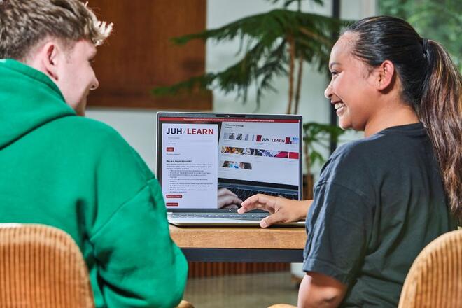 Zwei Freiwilligendienstleistende schauen gemeinsam auf einen Laptop.