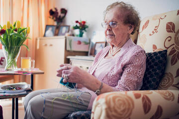 Dame mit Strickzeug im Sessel im Bewohnerzimmer