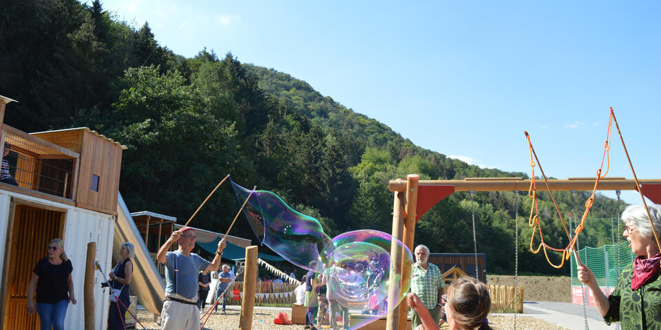 Ein Mann macht große Seifenblasen im Waldkindergarten