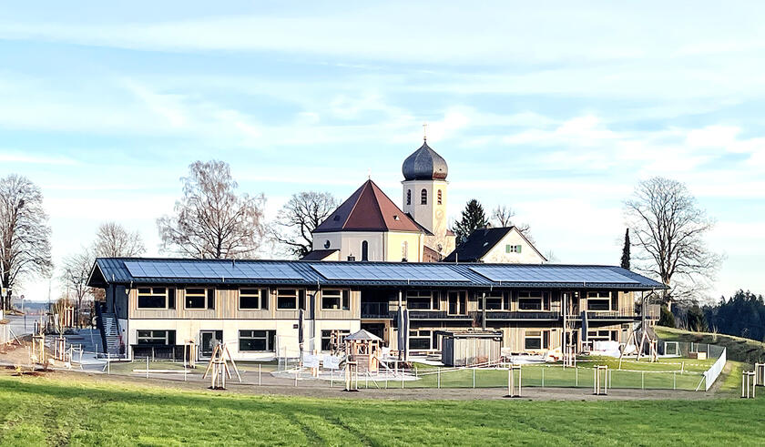 Der Neubau des Johanniter-Kinderhaus-Wildenwart vor der Kirche Christkönig in Wildenwart.