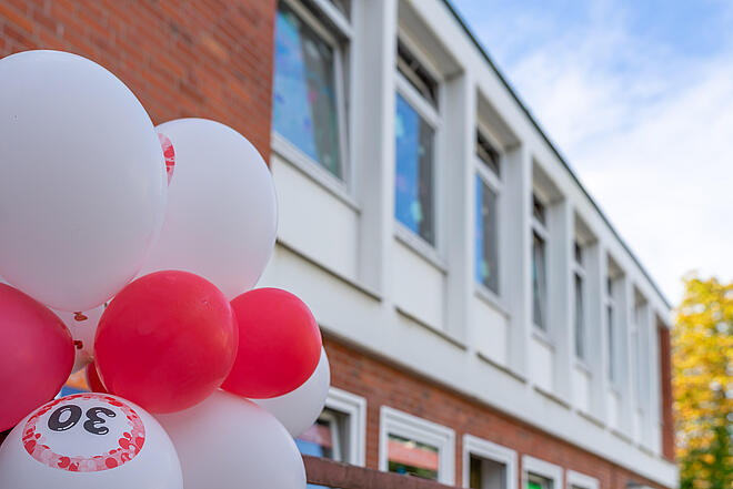 Rote und weiße Ballons mit der Aufschrift "30 Jahre" hängen vor dem Gebäude der Johanniter-Kita Stoppelhopser.