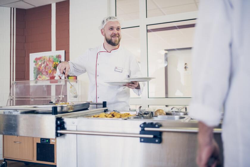 Ein Koch bei der Essensausgabe