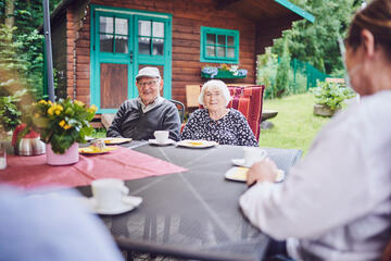 Ein älteres Paar sitzt an einem Tisch im Garten und lächeln