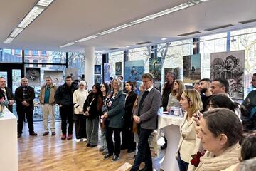 Zahlreiche Gäste stehen im Halbkreis und hören die Reden zur Eröffnung der Kunstausstellung.