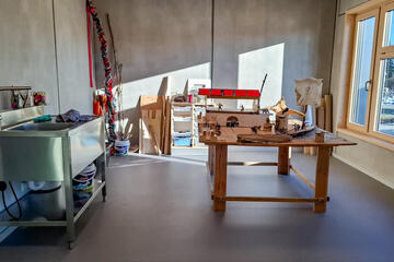 Werkraum im Hort mit Wasserbecken, Werkbank und Bastelmaterial am Fenster.