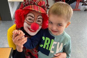 Ein Clown guckt mit einem kleinen Jungen gemeinsam in die Kamera.