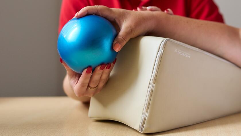 Zwei Hände greifen einen kleinen Ball.