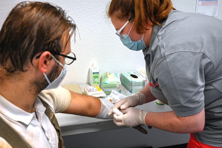 Johanniter-Sanitäterin versorgt die Armwunde eines Mannes und legt einen Verband an.