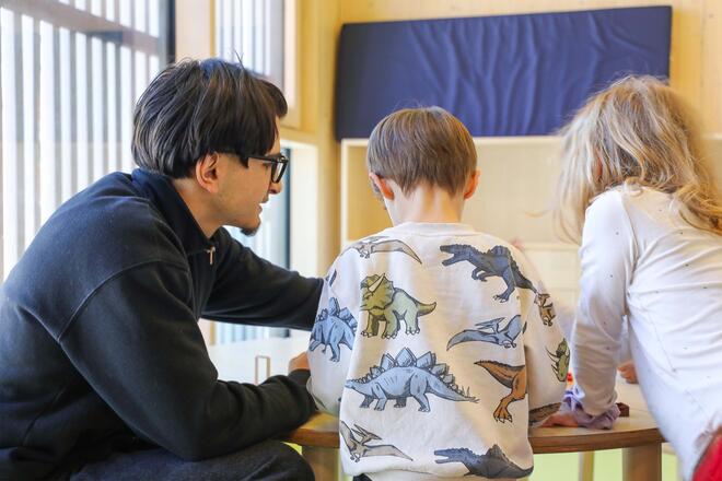 Junge vom Boys Day spielt mit Kindern im Kinderhaus..