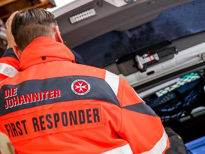 Sanitäter der Johanniter entnimmt am geöffneten Kofferraum Material.