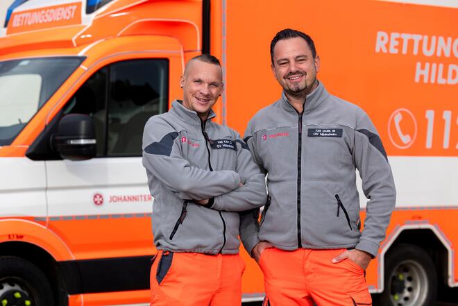 Zwei Männer in Johanniter-Kleidung vor einem Rettungswagen