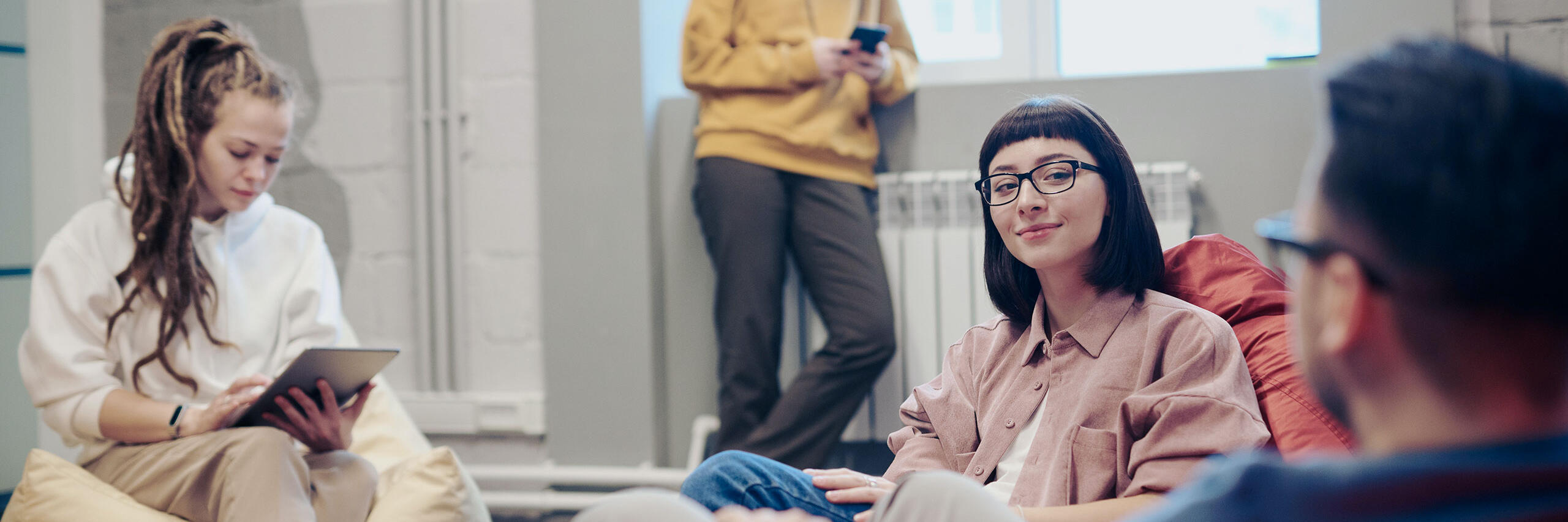 Junge Menschen sitzen während ihres FSJ zusammen und machen Pause auf bequemen Stühlen.