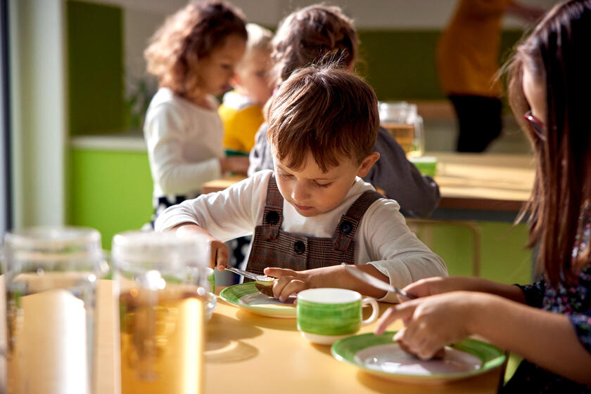 Ein Kind in einer KiTa schmiert sich ein Brot.