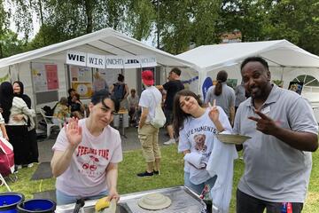 Drei Helfende posieren für das Foto, sie stehen beim Abwasch auf dem Festgelände.