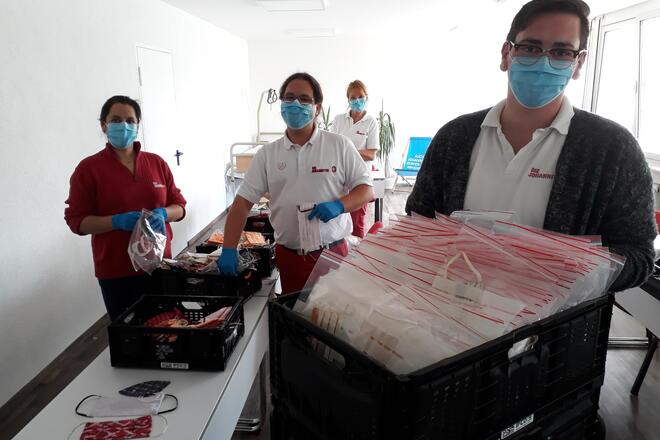 Mitarbeiter der Sozialstation verpacken gespendete Behelfsmasken hygienisch.