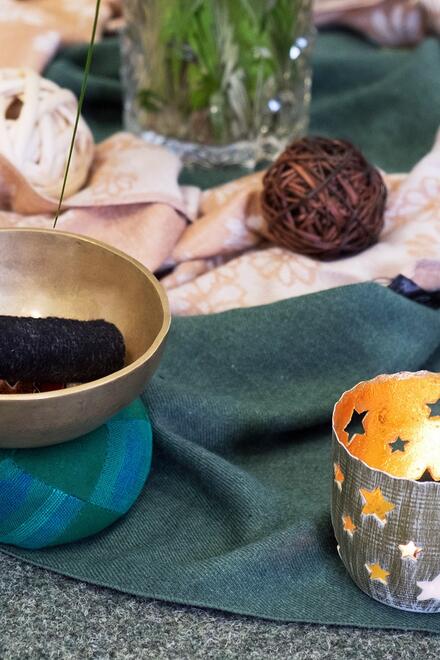 Eine Kerze und KLangschale stehen auf einem Tuch auf einem Tisch