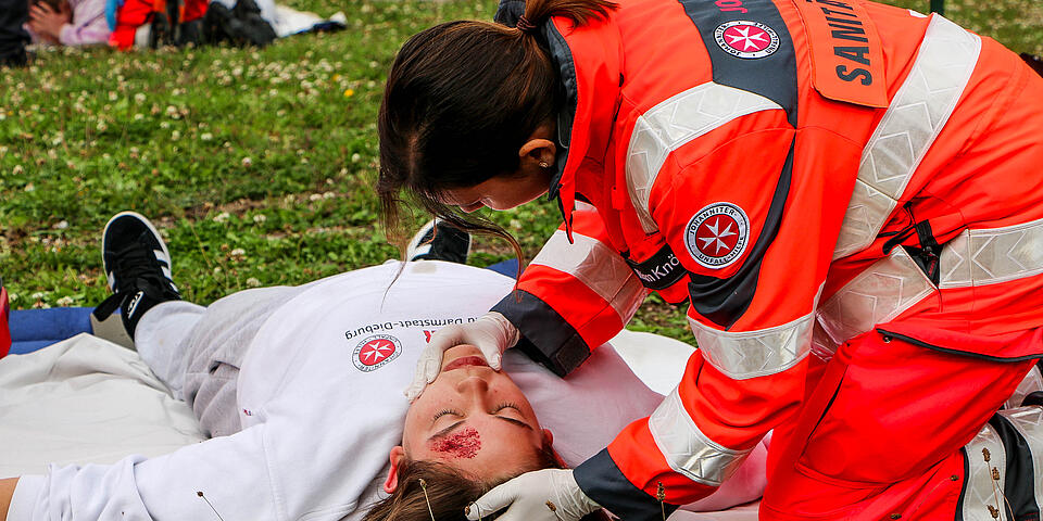 Helferin untersucht realistisch geschminkte Unfalldarstellerin