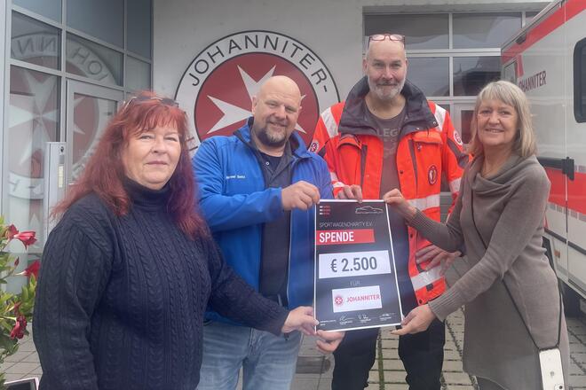 Evelyn Zelnhefer (links) und Annett Obermeyer vom Team Sportwagencharity sowie Vorstandmitglied der Johanniter Michael Seitz mit Carsten Döring aus dem Bereich Sanitätsdienste bei der Spendenübergabe