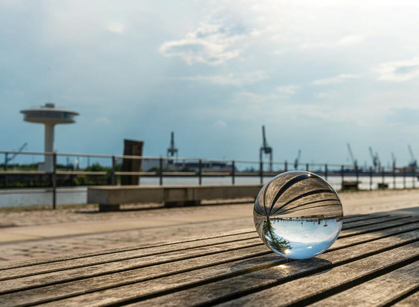 eine Glaskugel liegt auf einem Holzsteg am Hamburger Hafen 