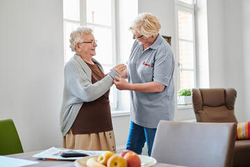 Johanniter-Pflegerin hilft älterer Dame im eigenen Zuhause 